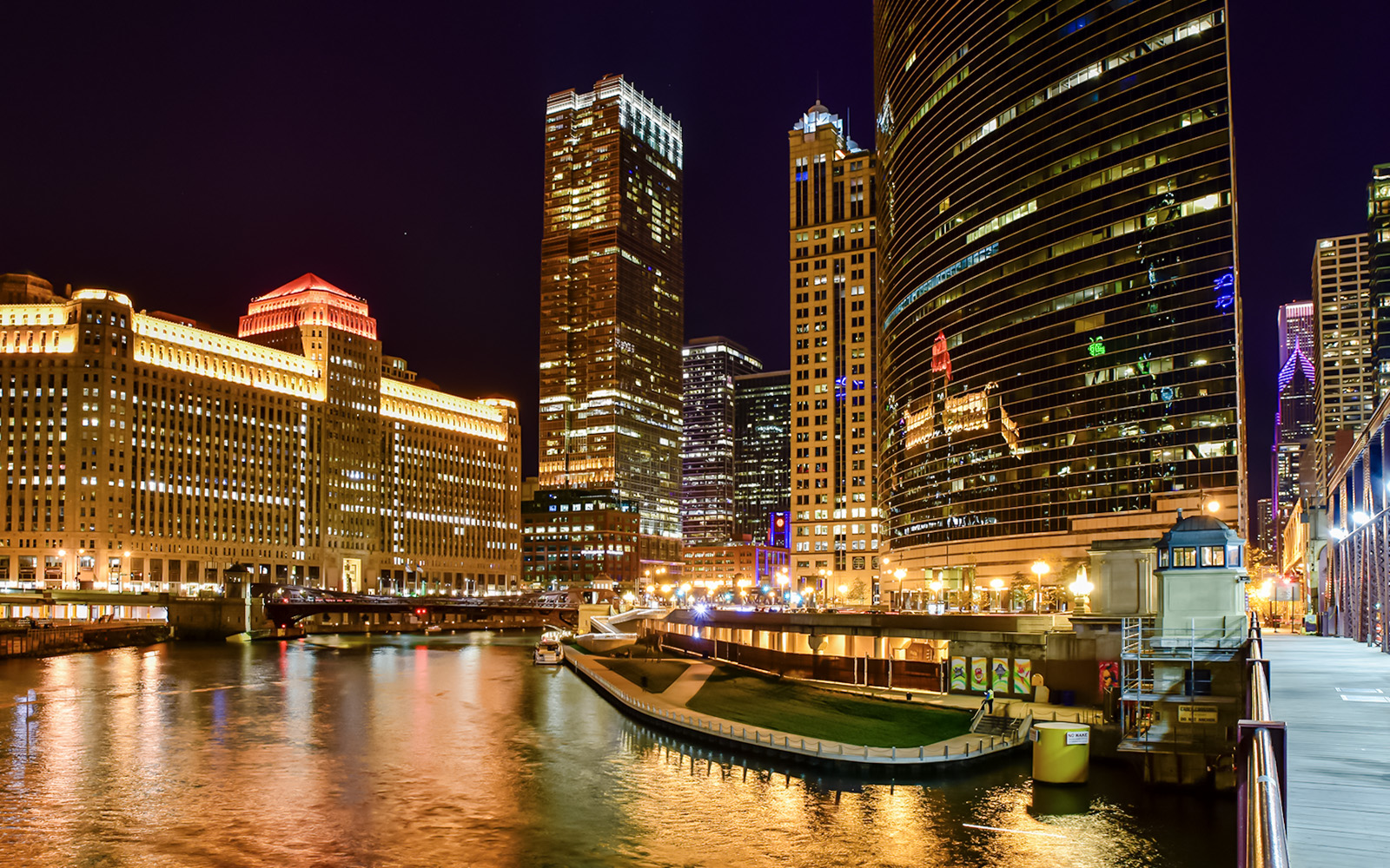 Chicago River at night with illuminated skyscrapers and reflections on the water.