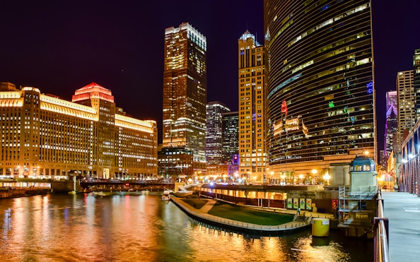 Chicago River at night with illuminated skyscrapers and reflections on the water.
