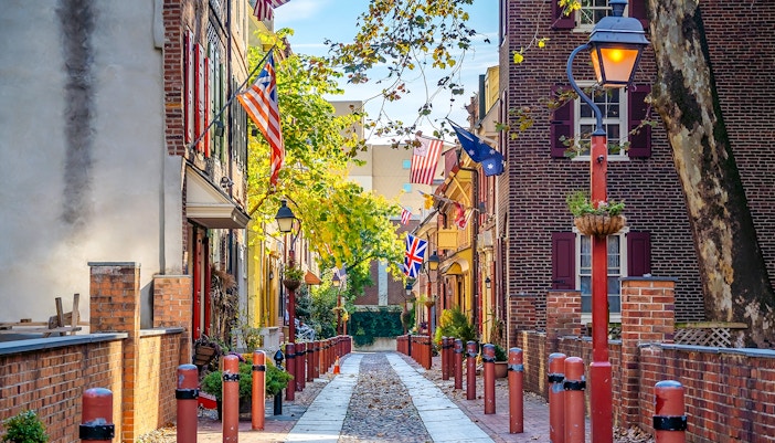 Elfreth's Alley in Philadelphia's historic Old City with flags and cobblestone path.