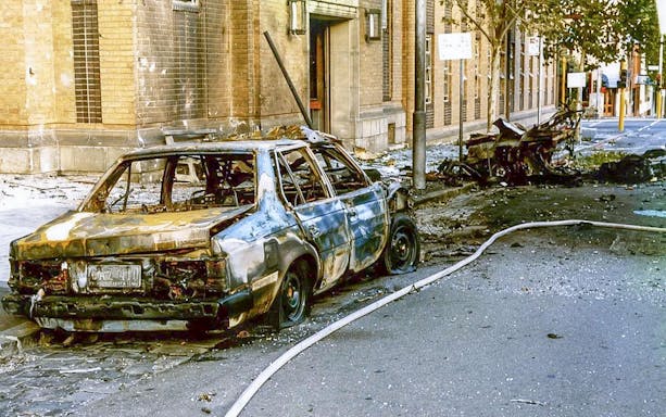 Burnt car on a Melbourne street, highlighting past crime scene for guided walking tour.