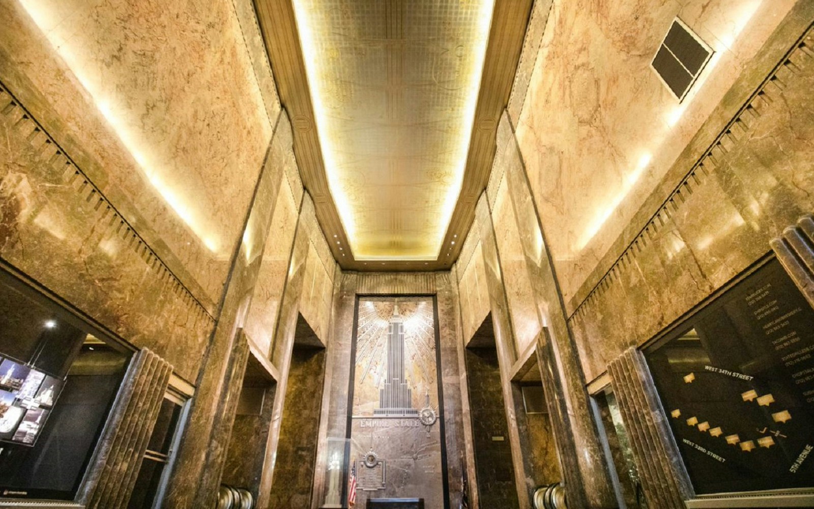 Empire State Building Art Deco lobby with golden ceiling and mural.