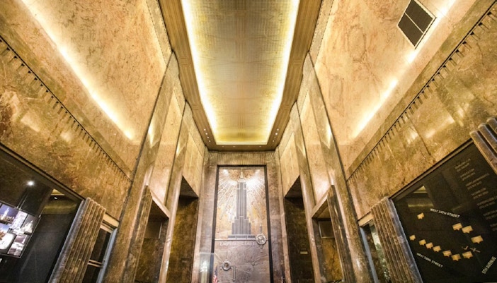 Empire State Building Art Deco lobby with golden ceiling and mural.