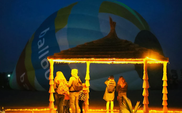 Group of people watching a hot air balloon inflate at dawn in Marrakech.