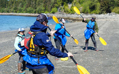 Kayakers preparing on a beach for a whale-watching tour in Juneau.