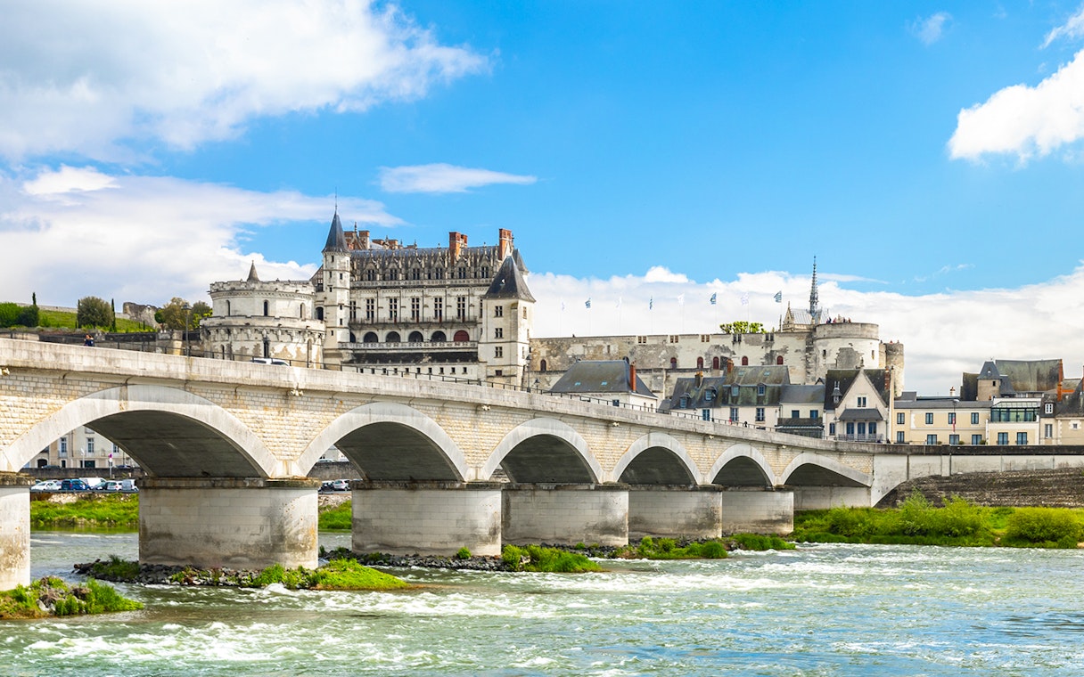 Bridge leading to Blois Castle in France with river in foreground.