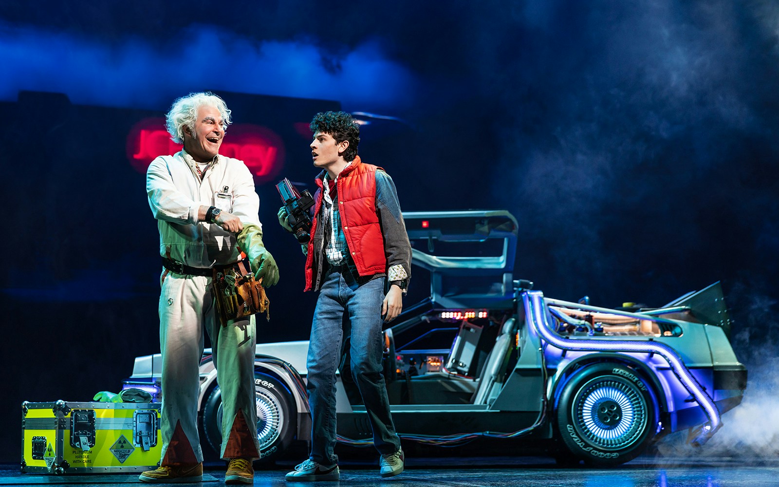 Two actors on stage with a DeLorean car in "Back to the Future the Musical.