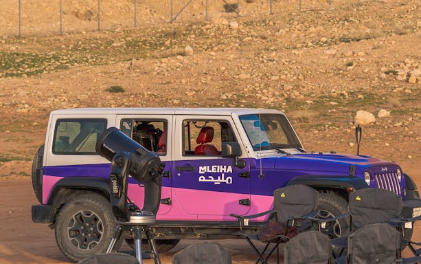 Stargazing setup with telescope and jeep in Mleiha desert.
