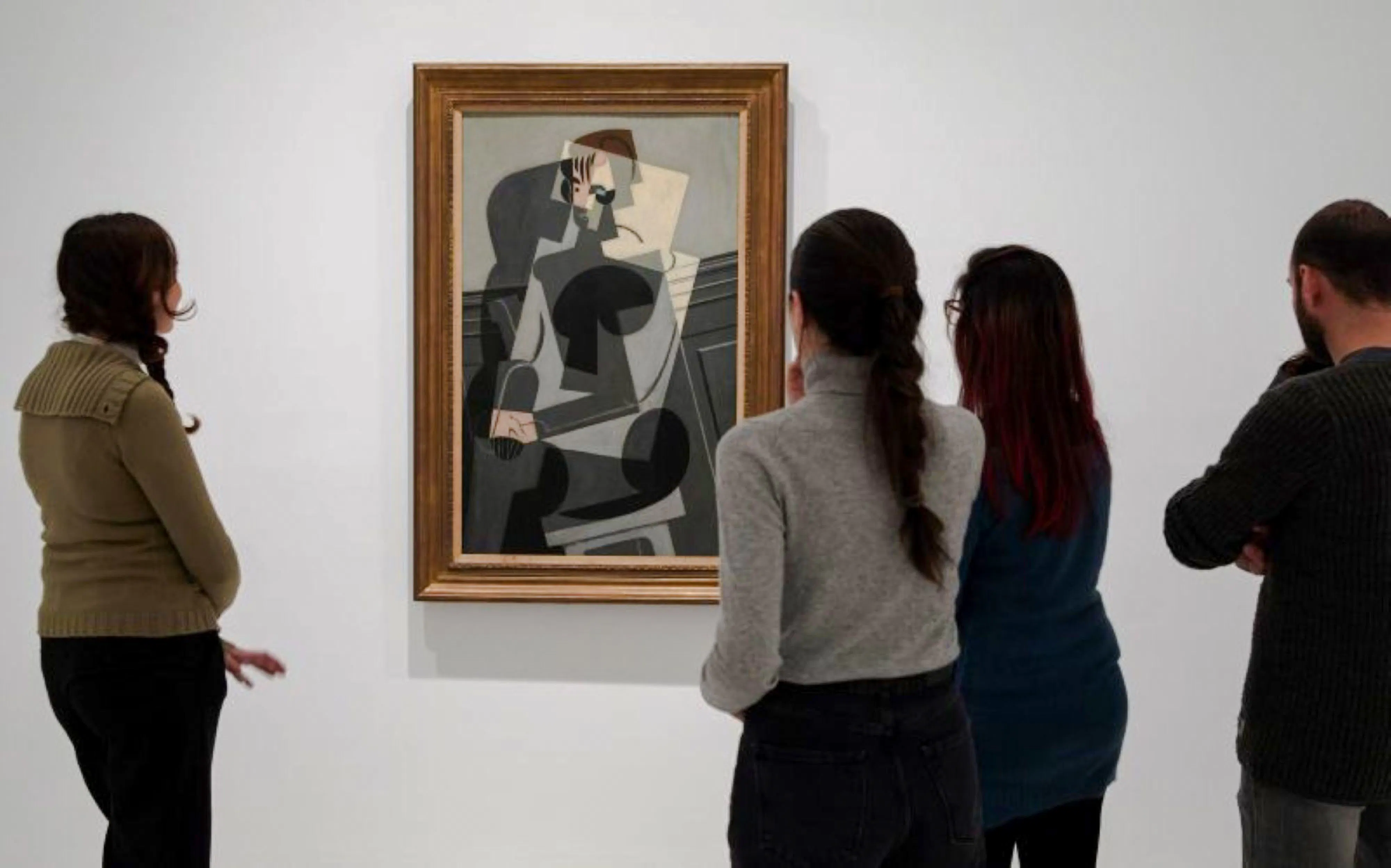 Visitors viewing a cubist painting at Reina Sofia Museum.