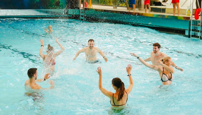 People enjoying the wave pool at Galaxy Zone, Therme Bucharest at night.