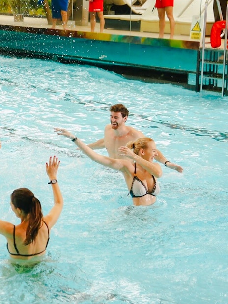 People enjoying the wave pool at Galaxy Zone, Therme Bucharest at night.