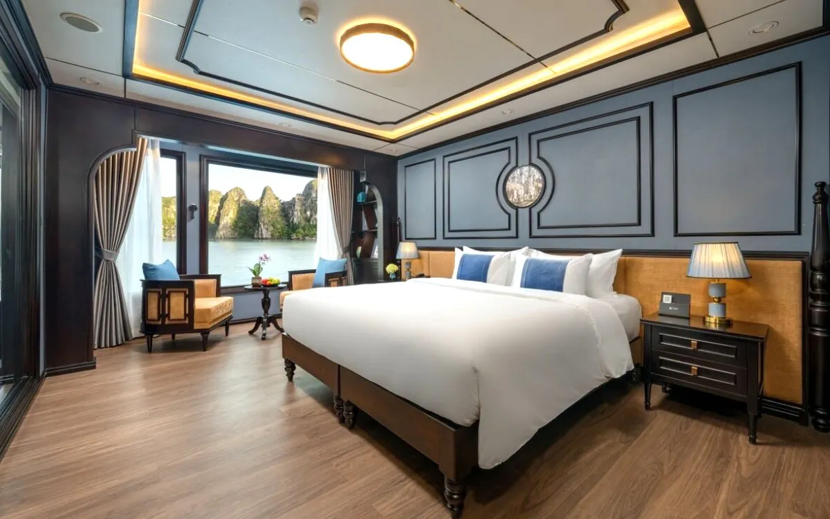 Grace Ocean suite interior with large bed, seating area, and window view of Ha Long Bay limestone karsts.