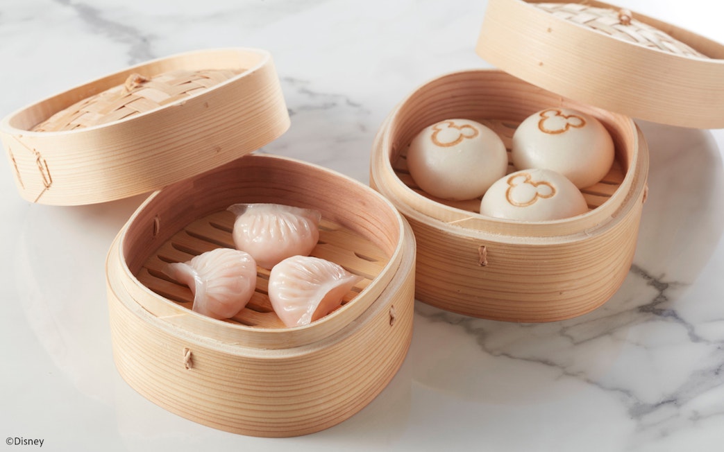 Steamed dumplings and buns with Mickey Mouse logo in bamboo baskets at Disneyland Hong Kong.