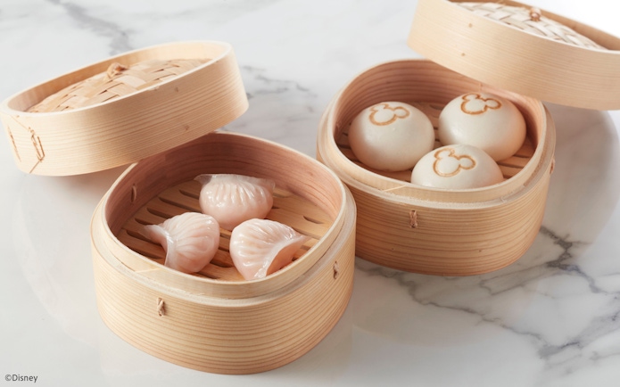 Steamed dumplings and buns with Mickey Mouse logo in bamboo baskets at Disneyland Hong Kong.