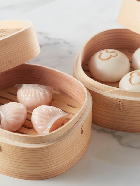 Steamed dumplings and buns with Mickey Mouse logo in bamboo baskets at Disneyland Hong Kong.