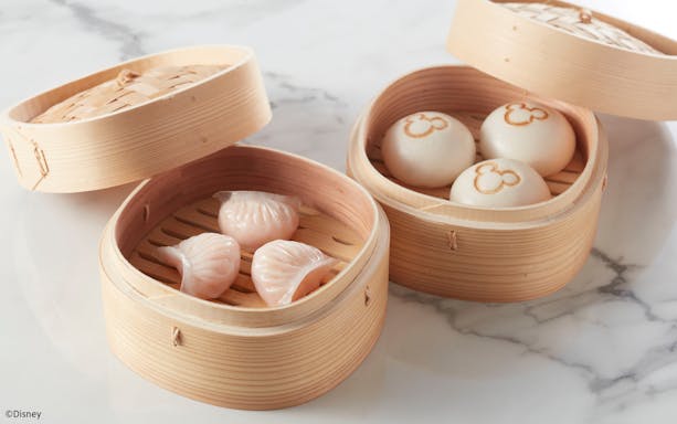 Steamed dumplings and buns with Mickey Mouse logo in bamboo baskets at Disneyland Hong Kong.