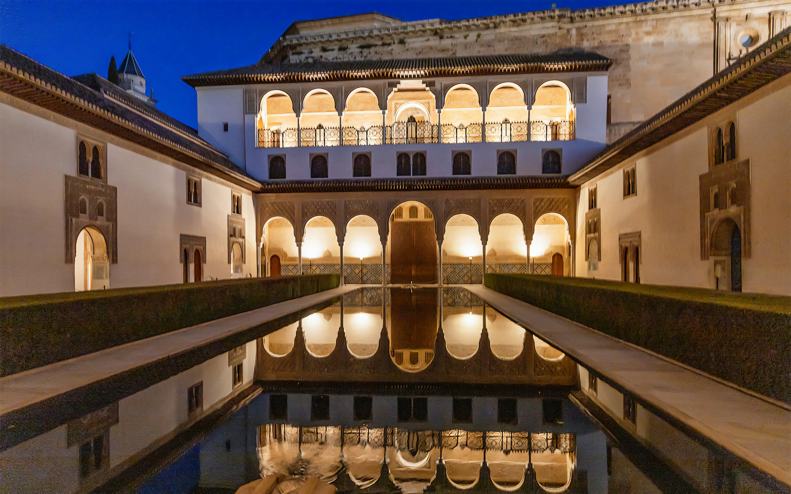 Reflection of Nasrid Palaces in Alhambra's courtyard pool at night, Granada, Spain.
