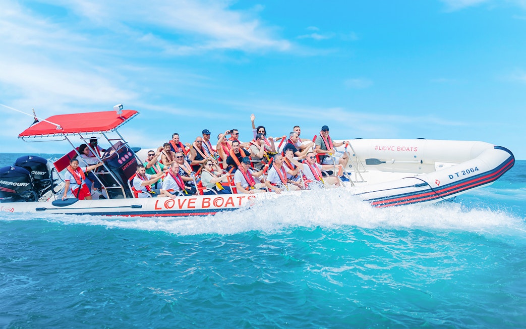 Group enjoying a Love Boats marina tour on a speedboat in clear blue waters.