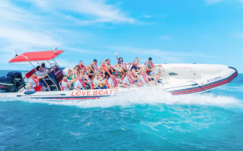 Group enjoying a Love Boats marina tour on a speedboat in clear blue waters.