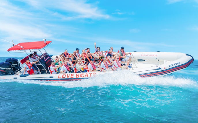 Group enjoying a Love Boats marina tour on a speedboat in clear blue waters.