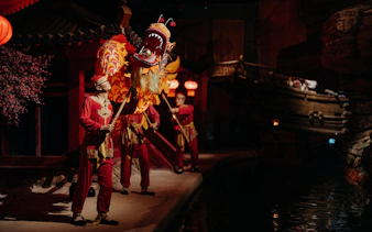 Performers in traditional attire with dragon puppet at World of Discoveries Interactive Digital Exhibition.