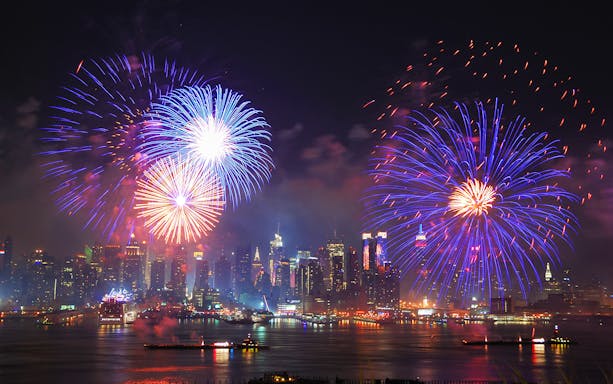 Fireworks display over New York City skyline at night.