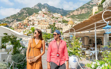 Couple walking in Positano with colorful hillside buildings in the background, Amalfi Coast tour.