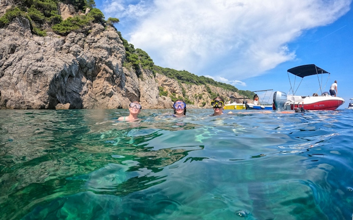 Snorkelers in clear water near rocky cliffs on Dubrovnik boat tour to Blue Cave and Elaphiti Islands.