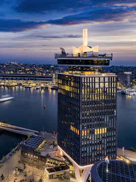 A'DAM Lookout tower overlooking Amsterdam at dusk with city lights and river.