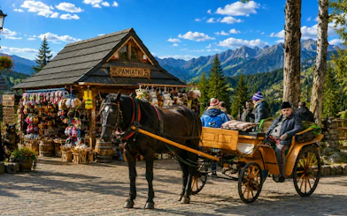 Horse-drawn carriage near souvenir shop in Zakopane with Tatra Mountains in background.