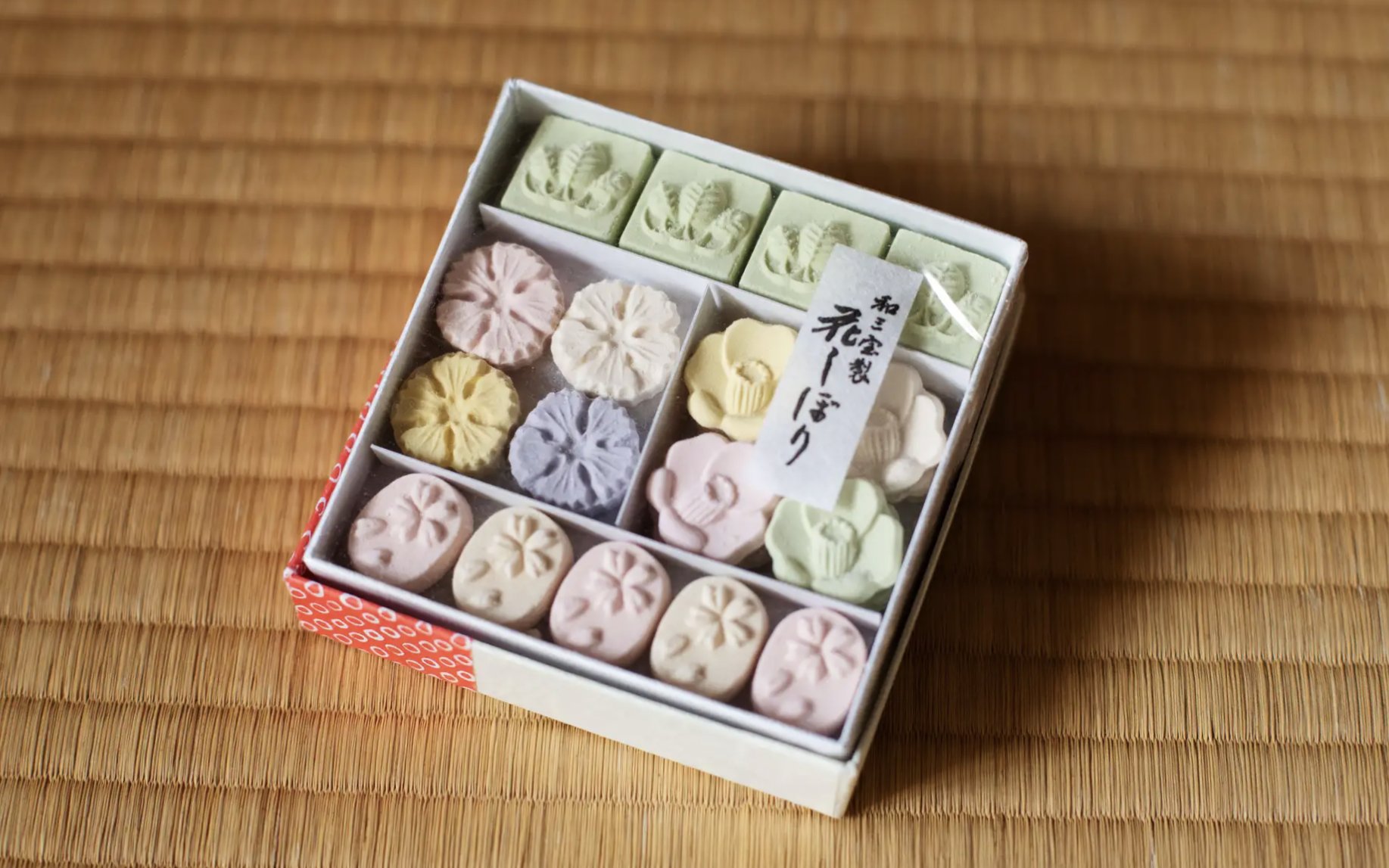 Box of traditional Japanese Wasanbon sugar sweets on tatami mat.