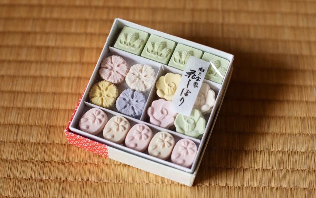 Box of traditional Japanese Wasanbon sugar sweets on tatami mat.