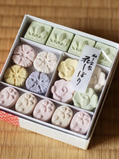 Box of traditional Japanese Wasanbon sugar sweets on tatami mat.
