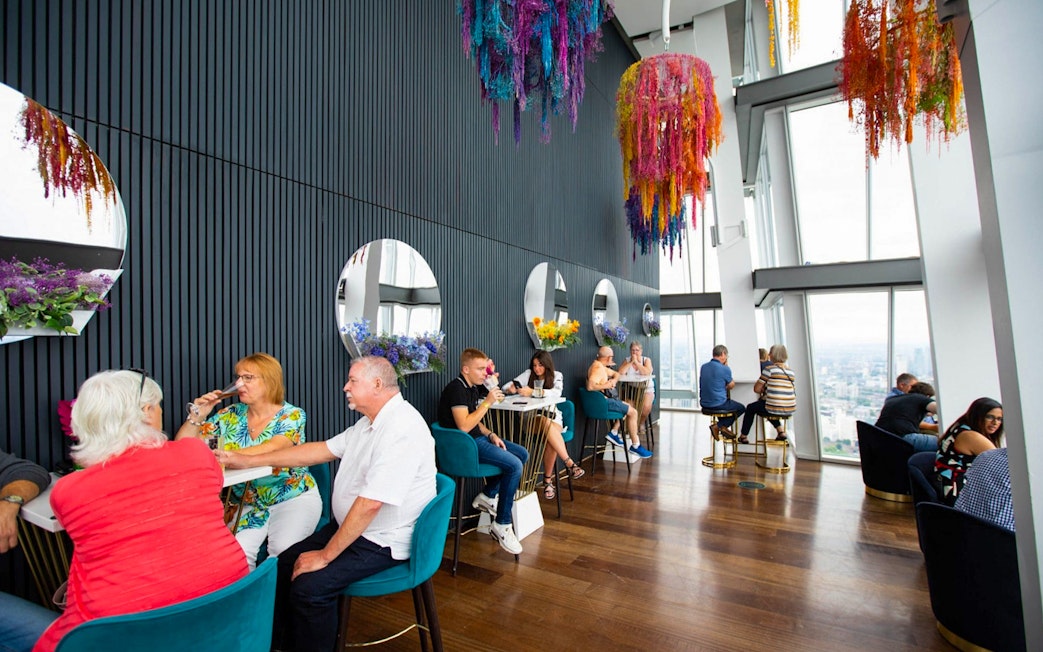 People enjoying drinks at a table with city views from the top of the Shard in London.