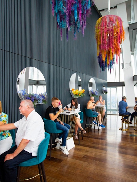 People enjoying drinks at a table with city views from the top of the Shard in London.