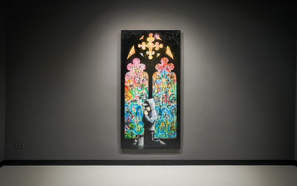 Artwork featuring colorful graffiti and a hooded figure at Moco Museum, Barcelona.