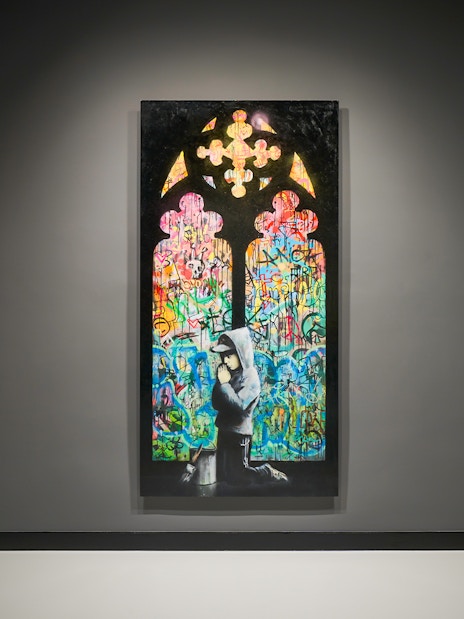 Artwork featuring colorful graffiti and a hooded figure at Moco Museum, Barcelona.