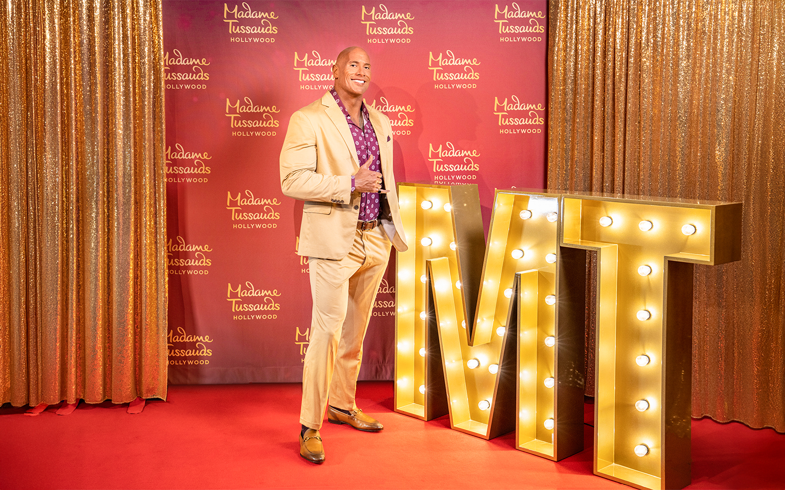 Dwayne Johnson statue at Madame Tussauds Hollywood with illuminated MT letters.