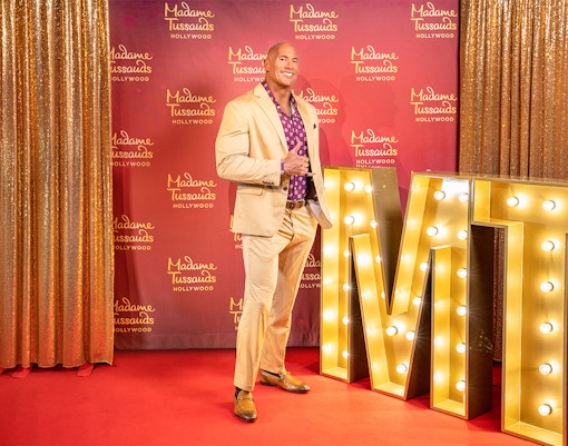 Dwayne Johnson statue at Madame Tussauds Hollywood with illuminated MT letters.