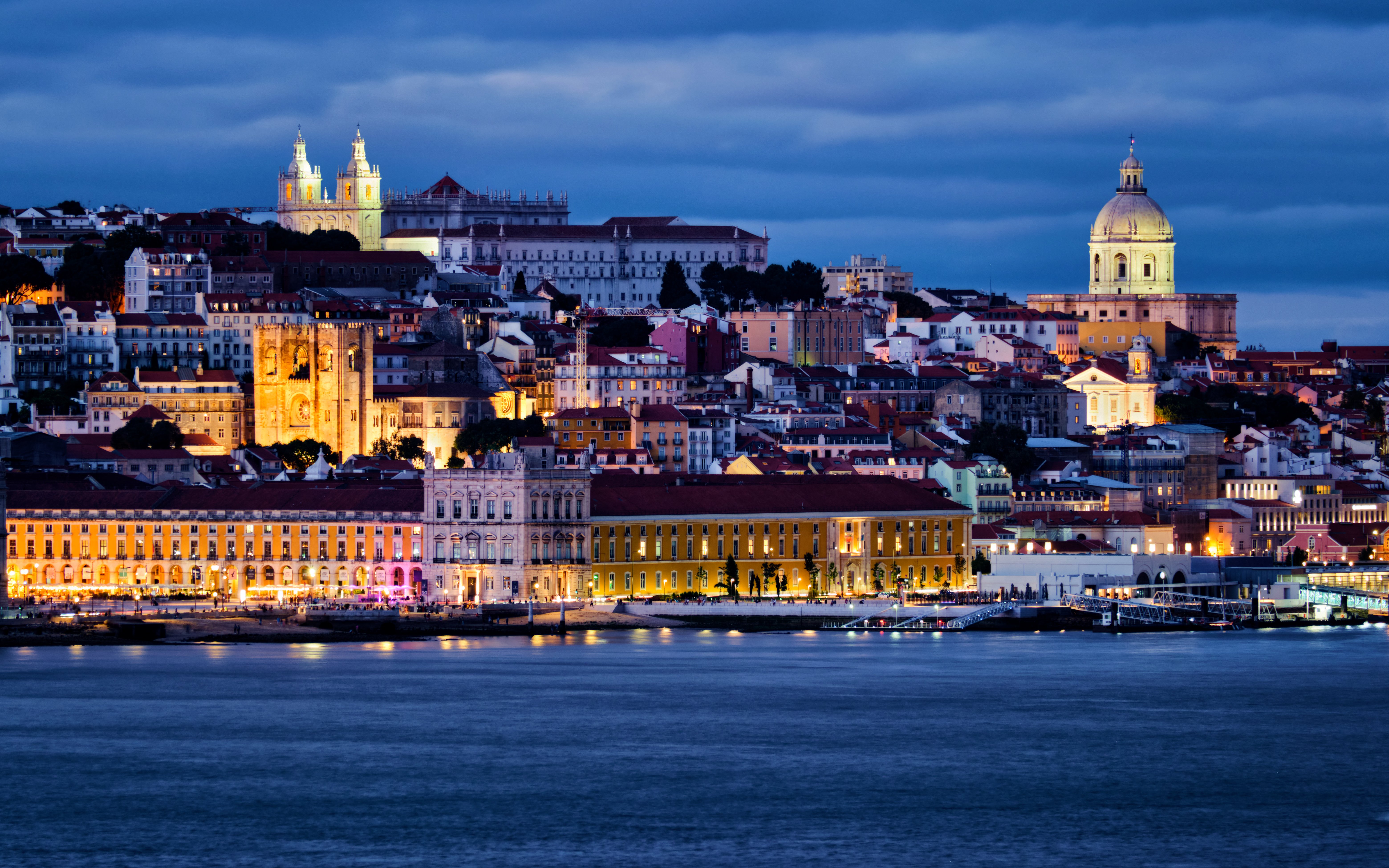 Lisbon view over Tagus River with Alfama district, National Pantheon, Monastery of St. Vincent, and ferry at twilight.