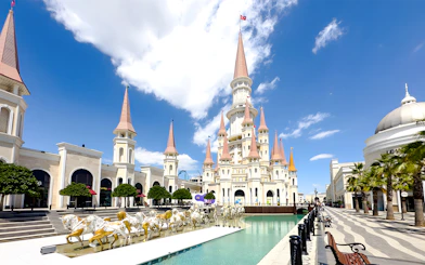 Land of Legends Themepark castle with spires and horse statues by a water feature.