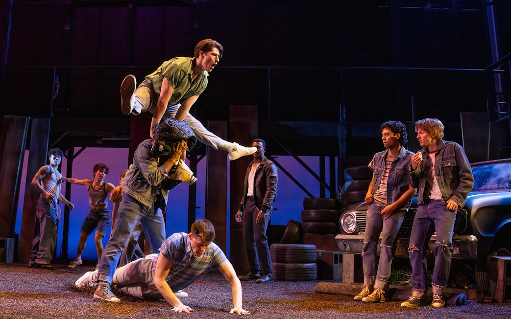 Stage performance of "The Outsiders" with actors in a dynamic scene.