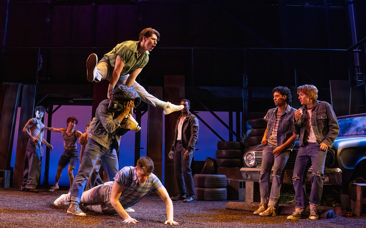 Stage performance of "The Outsiders" with actors in a dynamic scene.