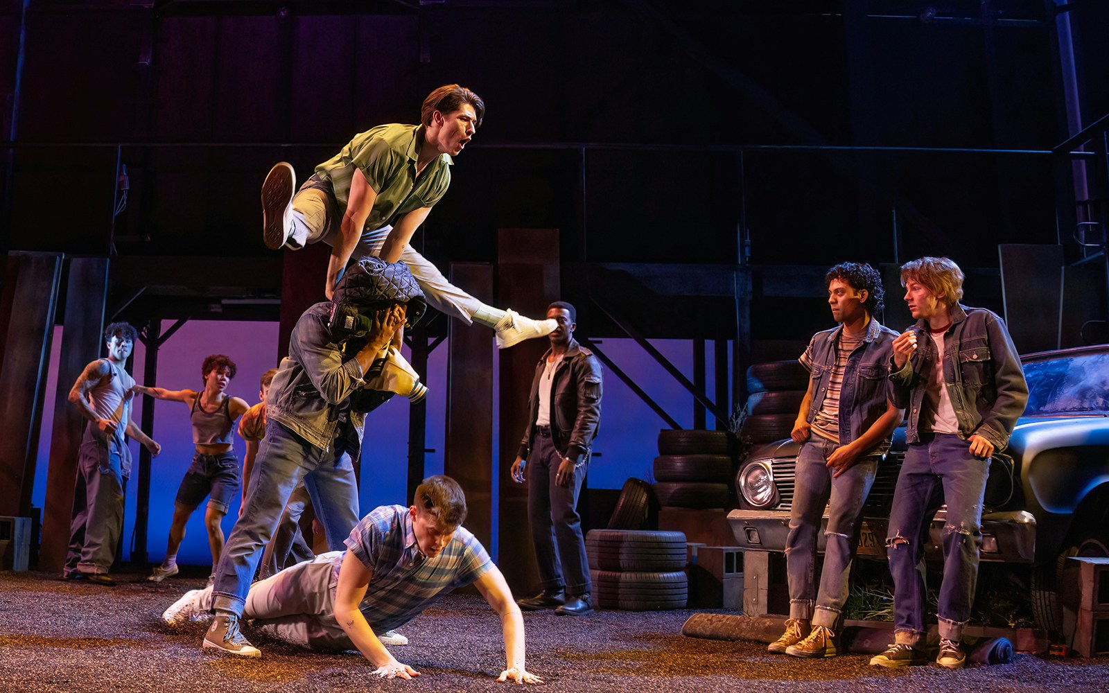 Stage performance of "The Outsiders" with actors in a dynamic scene.