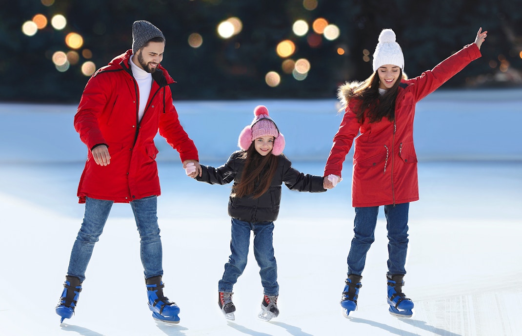 Family ice skating together at an outdoor rink.