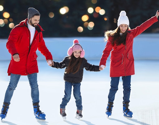 Family ice skating together at an outdoor rink.