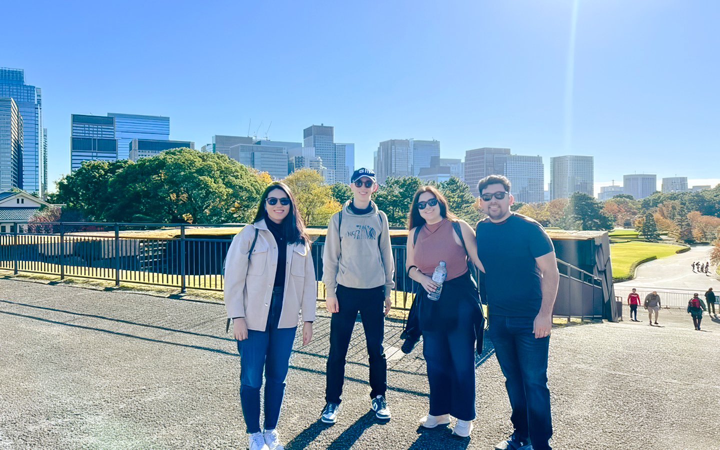 Visitors at Tokyo's Imperial Palace with city skyline in the background.