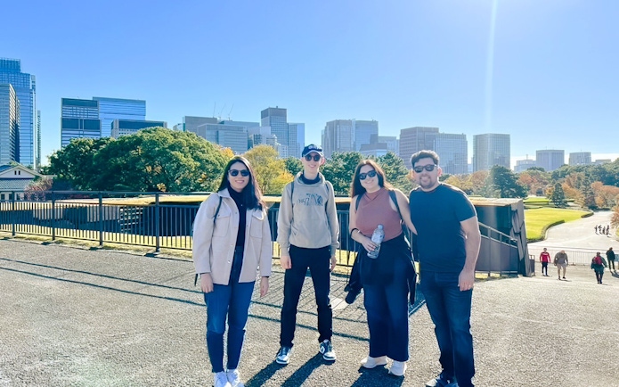 Visitors at Tokyo's Imperial Palace with city skyline in the background.