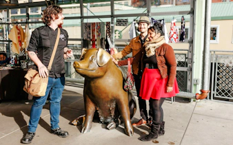 Visitors with a guide at Rachel the Piggy Bank statue, Pike Place Market, Seattle.