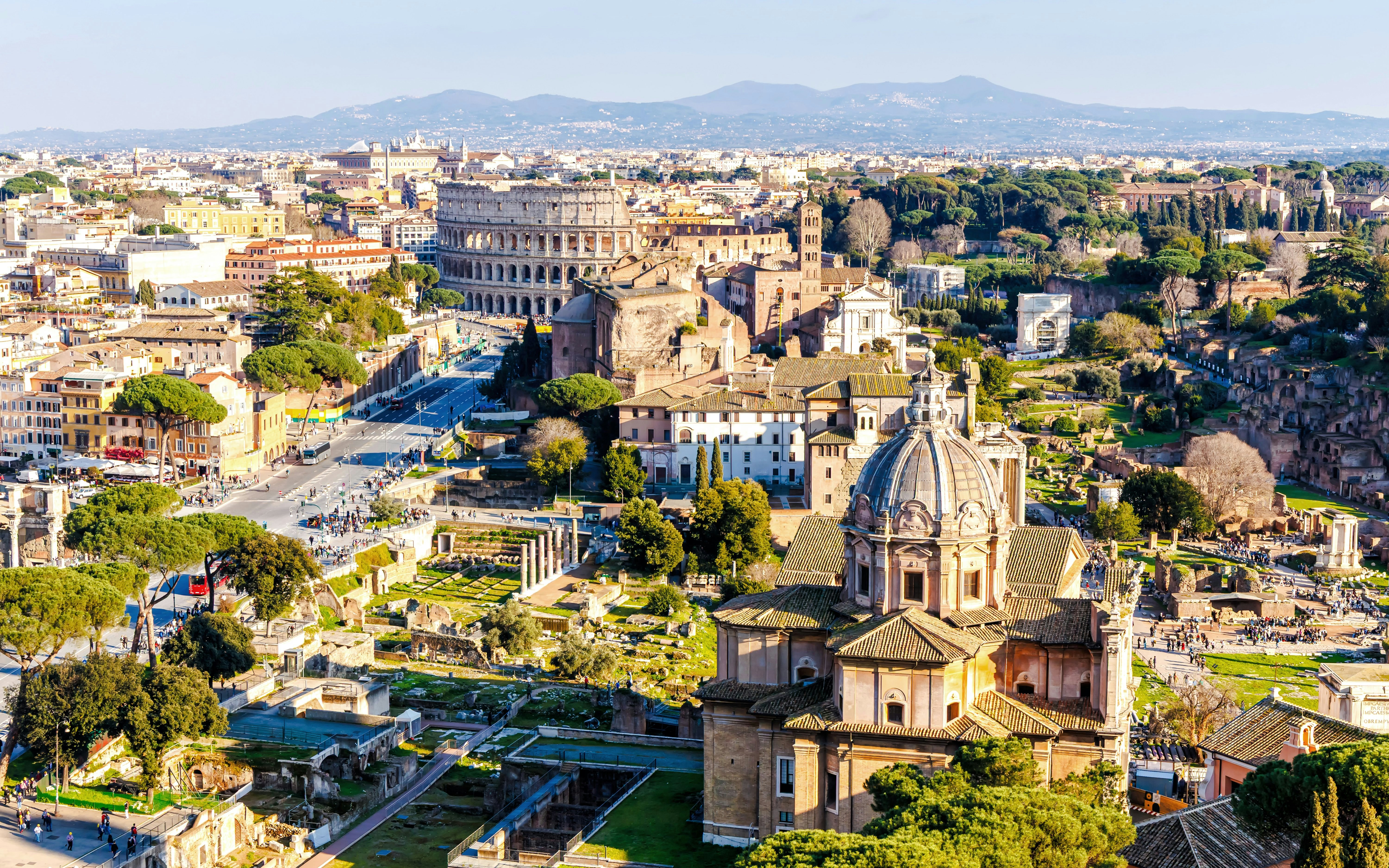 Aerial view of Rome skyline featuring the Colosseum and Roman Forum ruins in Italy.