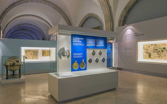 Astrolabe exhibit at Maritime Museum Lisbon with historical maps and globes.